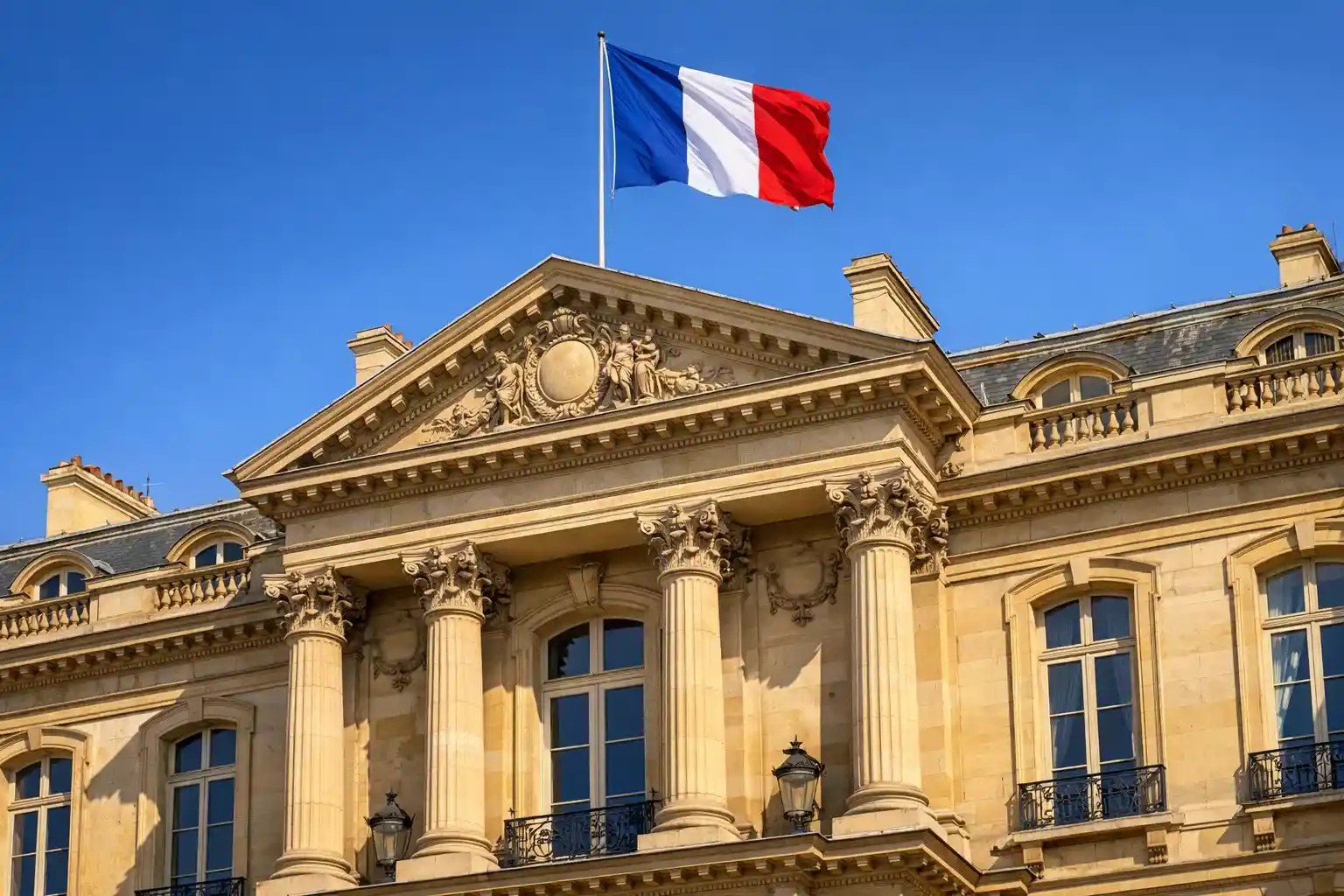 Façade d'un bâtiment officiel français avec un drapeau tricolore flottant au vent sous un ciel bleu