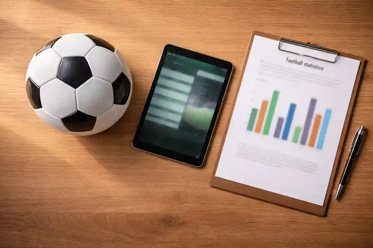 Vue rapprochée d'un écran affichant des statistiques de football avec un ballon de foot posé sur un bureau